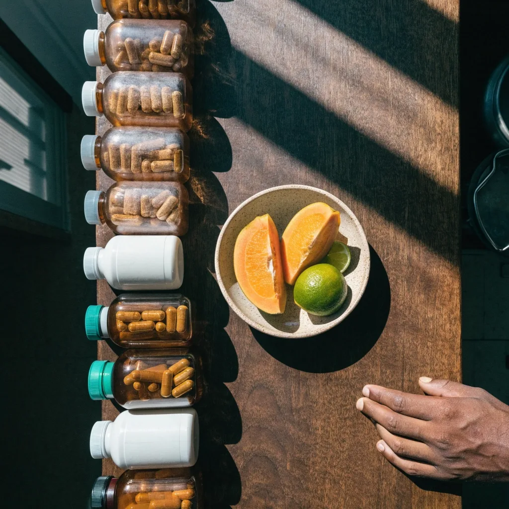 Unlabeled daily-use supplement bottles lined along a kitchen counter in morning daylight